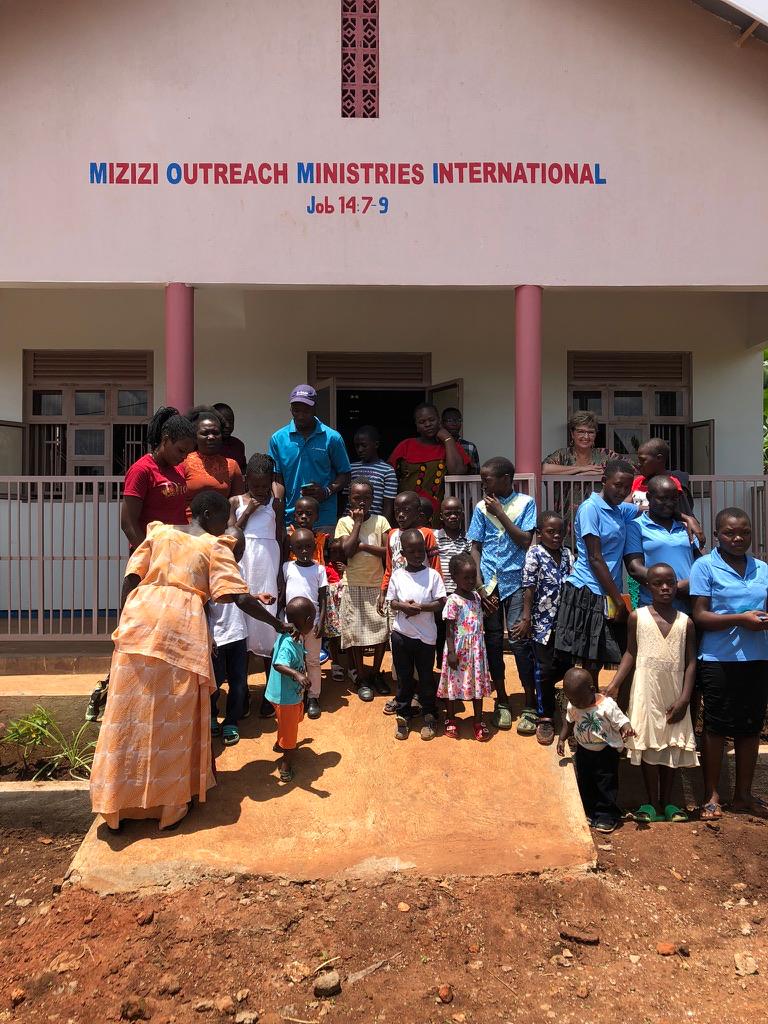 Mizizi Outreach Ministries International church in Kayunga, with community members and children gathered out front